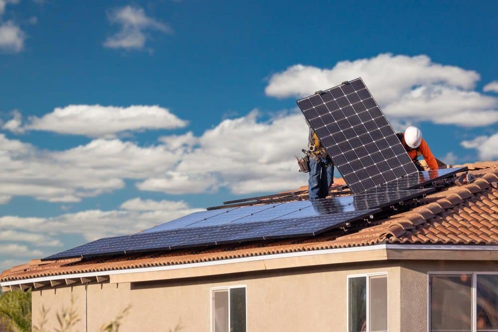 Trabajadores instalando paneles solares en el techo de la casa